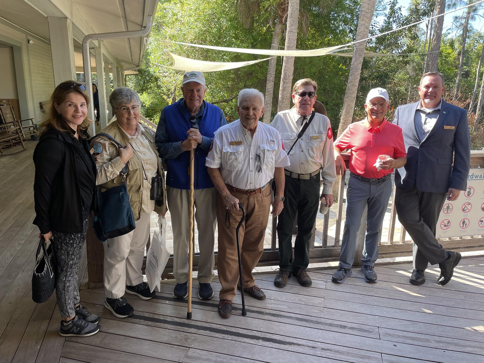 A group of people standing on a porch smiling for the camera