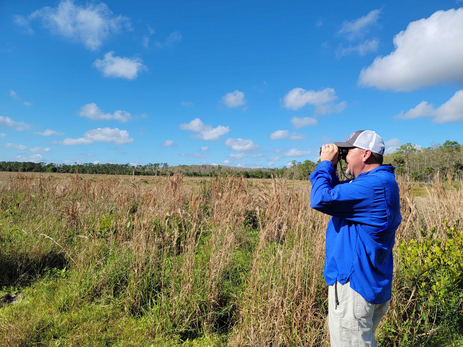 A man with binoculars in a field