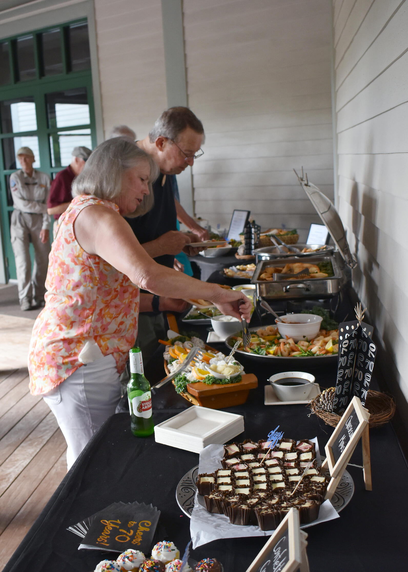 Photo of people serving themselves at a buffet table.