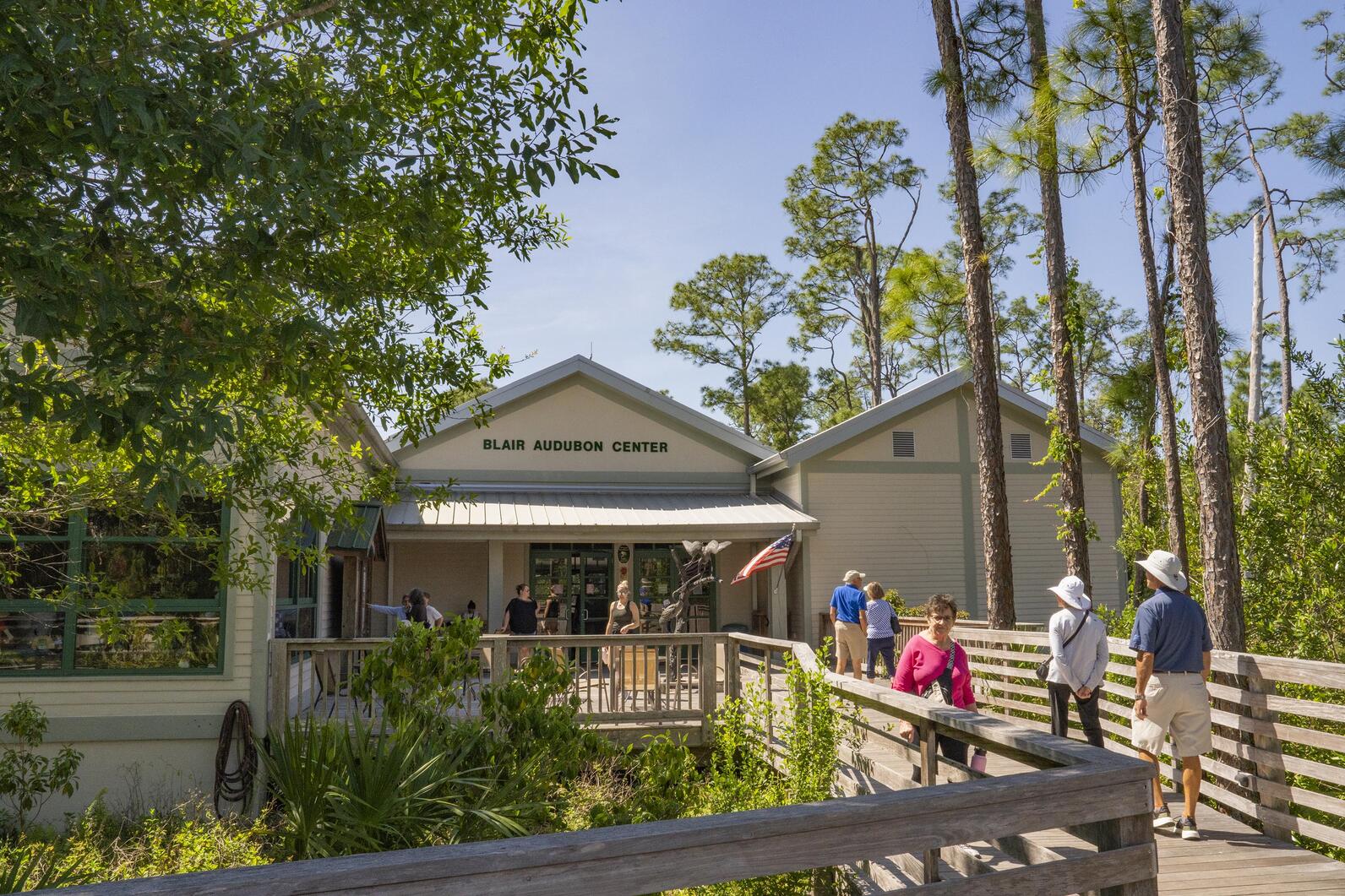 Photo of the visitor center exterior with people coming and going on the boardwalk.